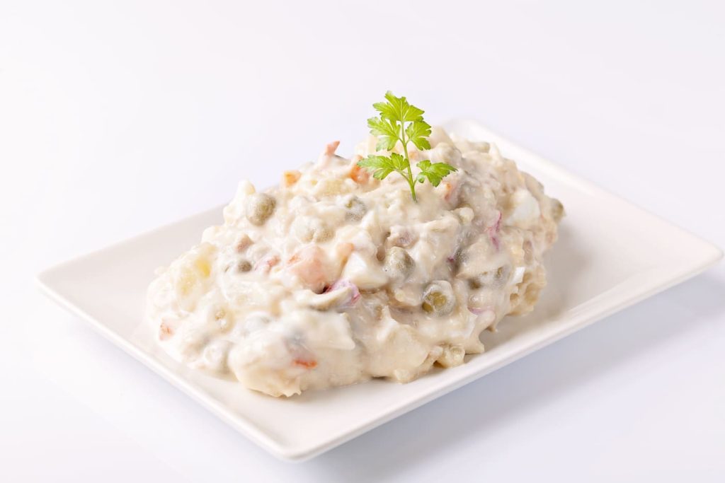 Plato de ensaladilla rusa en una mesa blanca