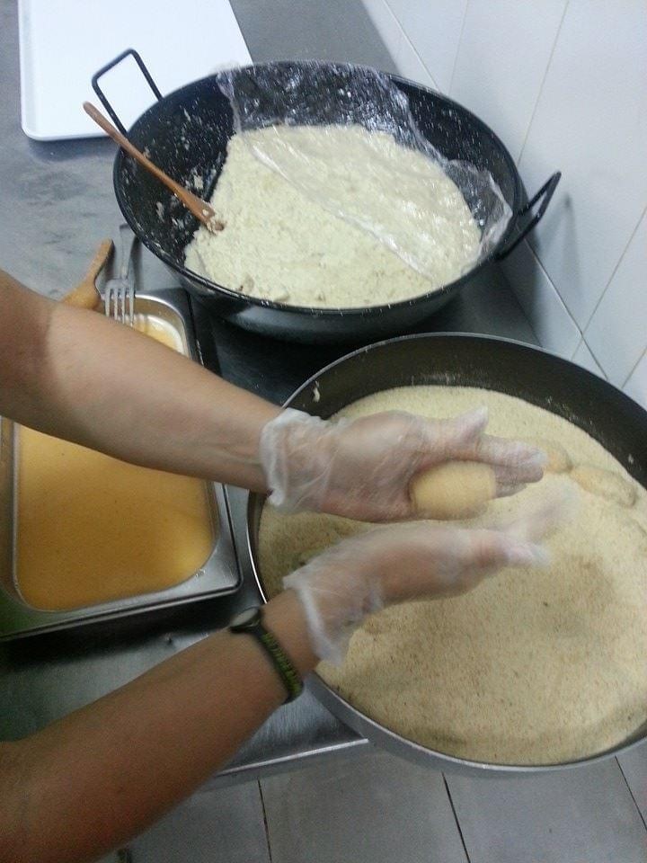 Proceso de preparación de alimentos en la cocina con masa y sartén de fritura.